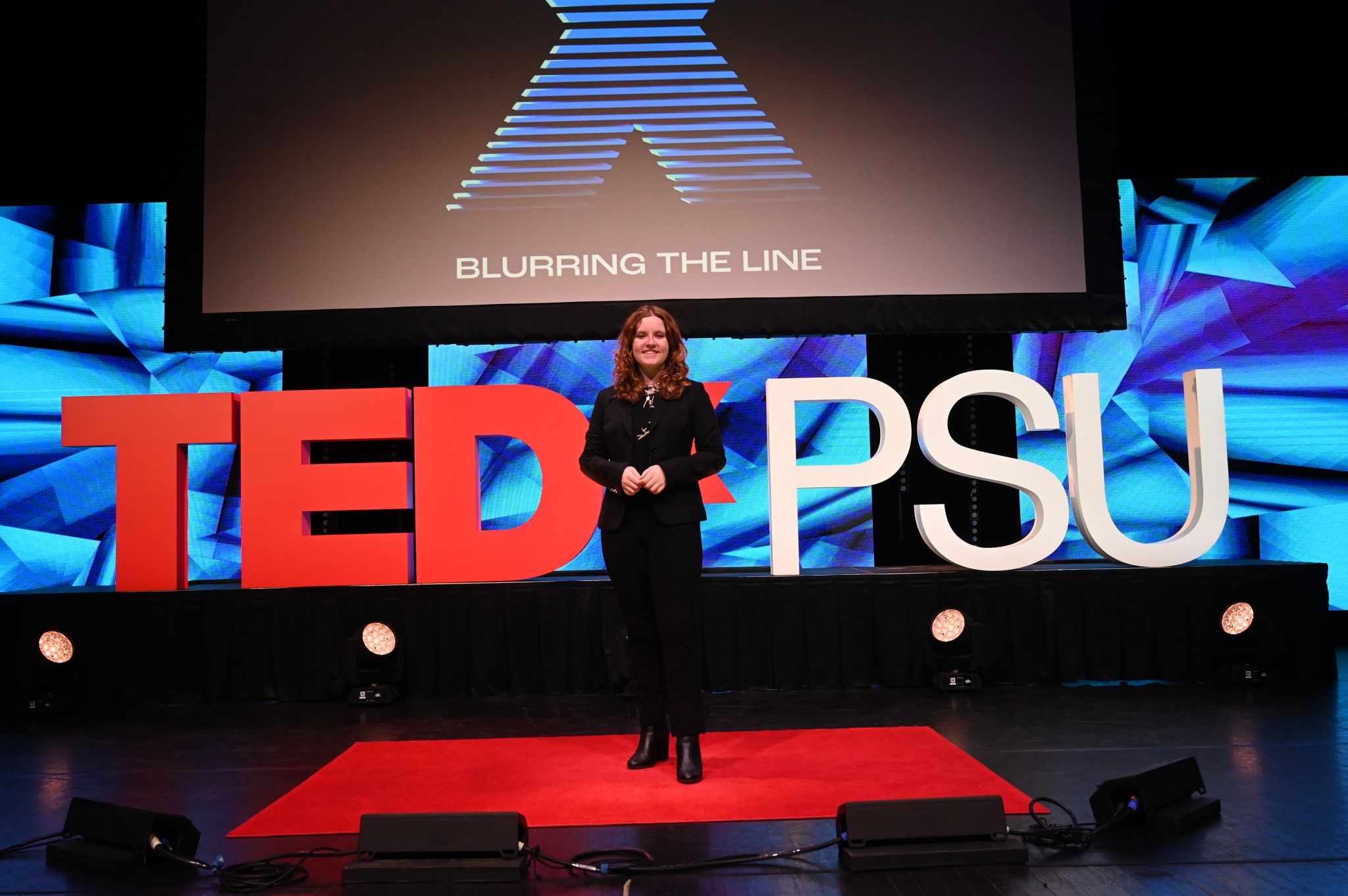 Natalie stands and poses on the TedxPSU Stage. 