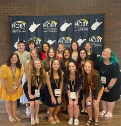 Spears, a fellow volunteer, and their group pose for a photo in front of a HOBY banner
