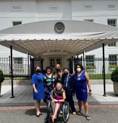 A group of people standing in front of a White House entrance wearing formal attire