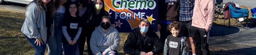 Members outside with Benny and Amelia standing in front of a sign that reads, "Benny says...no more chemo for me!"